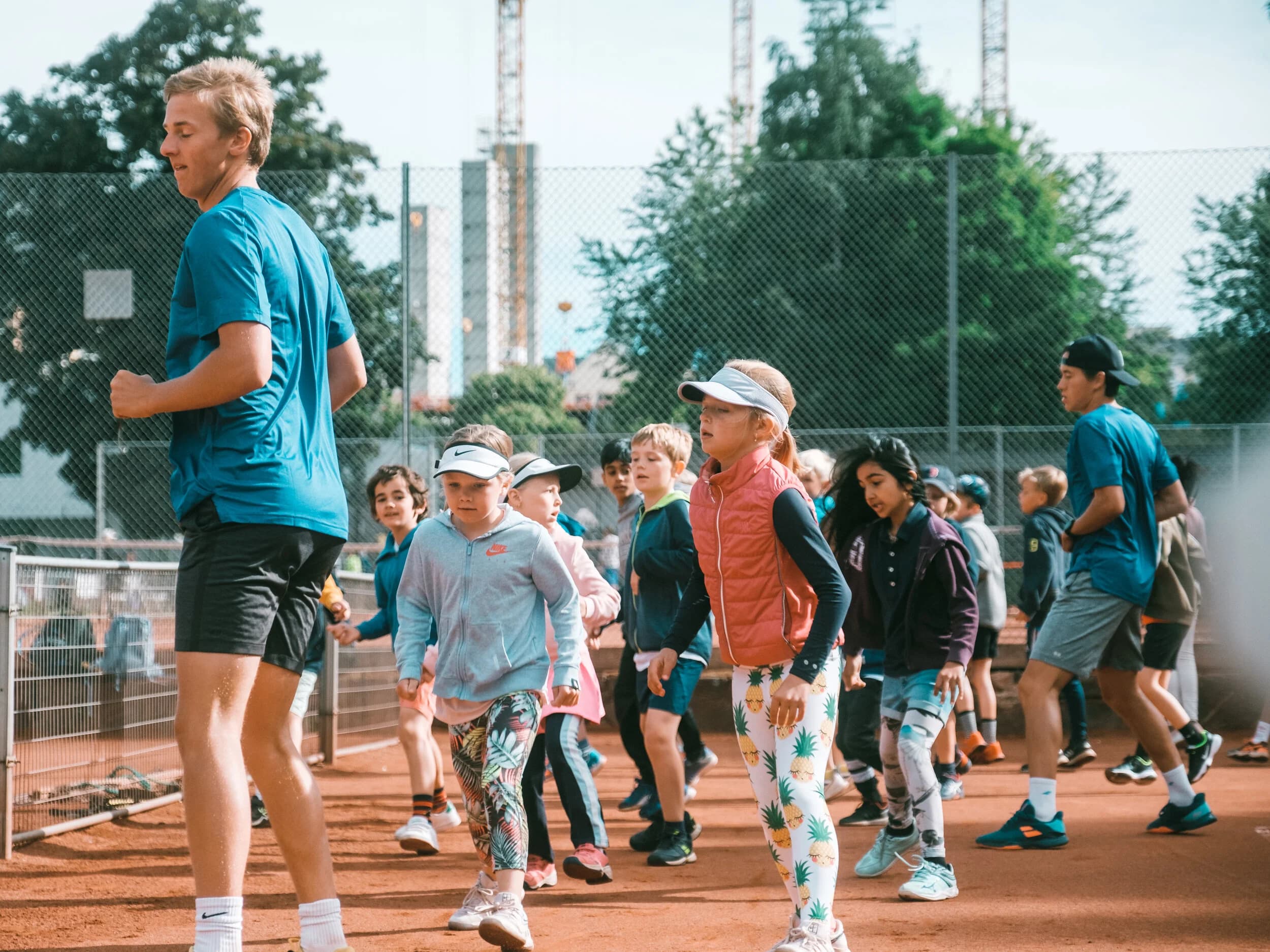 Barn på sommerkurs på tennisbanen